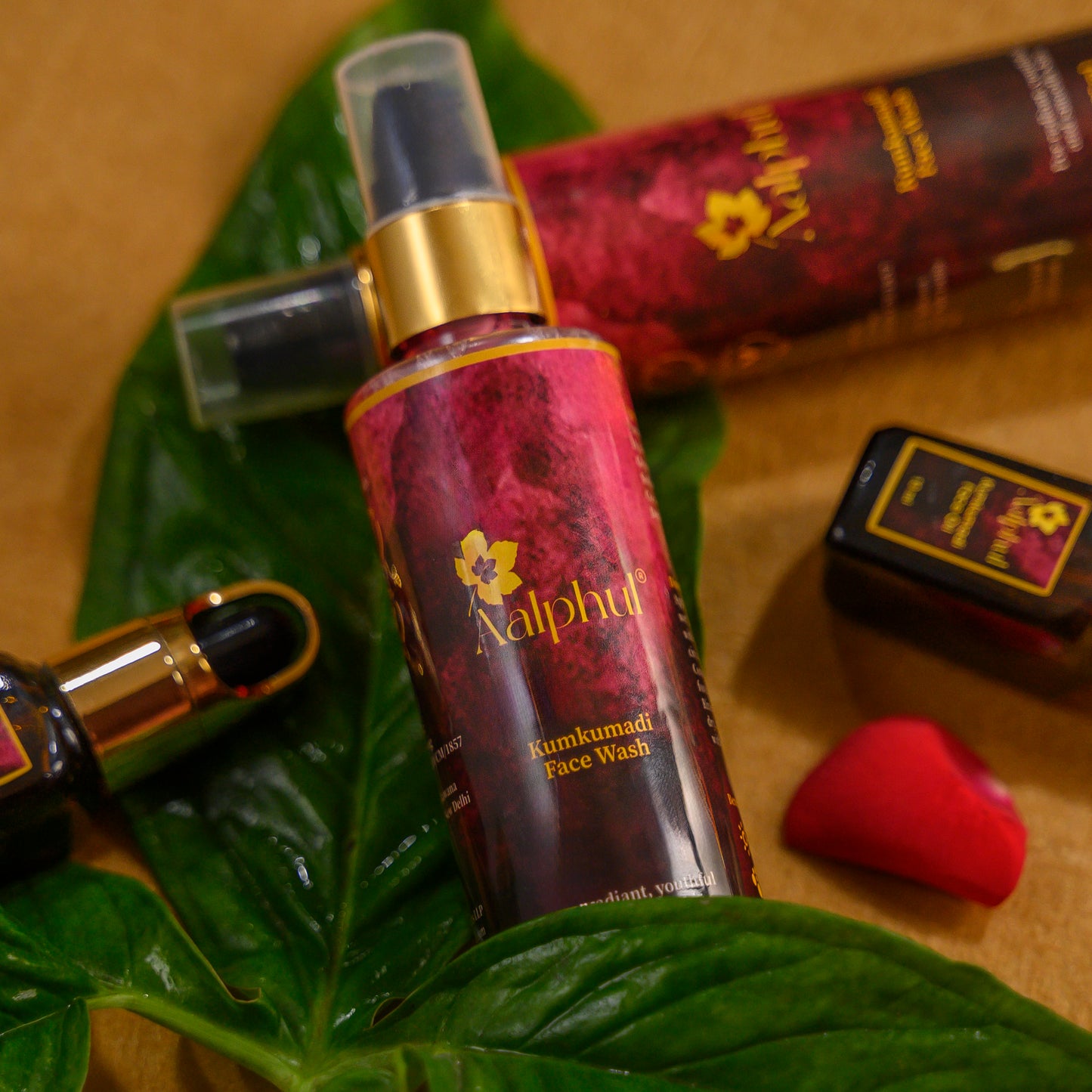 Aalphul Kumkumadi Face Wash bottle on a green leaf with other cosmetic products.