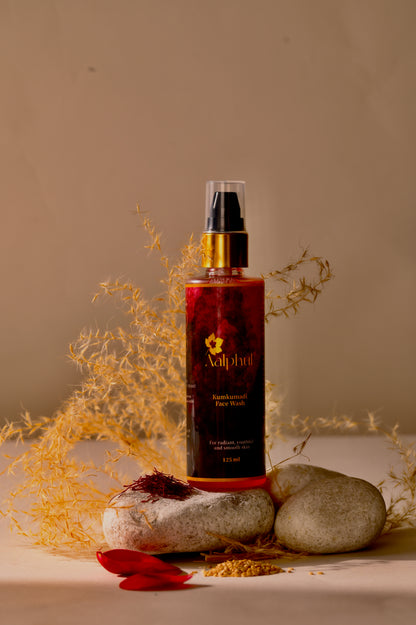 Aalphul Kumkumadi Face Wash bottle placed on stones displayed with natural herbs and floral elements