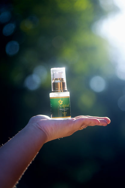 Aalphul Vitamin C Serum bottle held in a palm with a sunlit green background