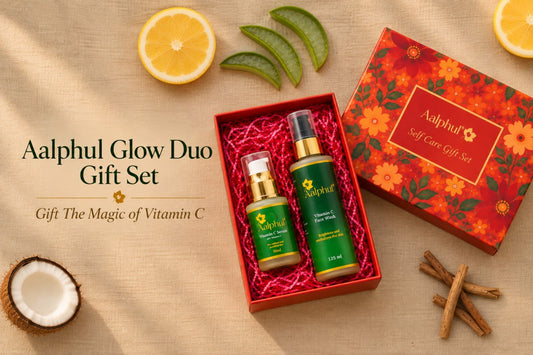 Aalphul Glow Duo Gift Set featuring a Vitamin C Serum and a Vitamin C Face Wash presented in a red gift box alongside its floral red and orange outer packaging, styled with lemon slices, aloe vera, cinnamon sticks, and a coconut on a beige fabric background.