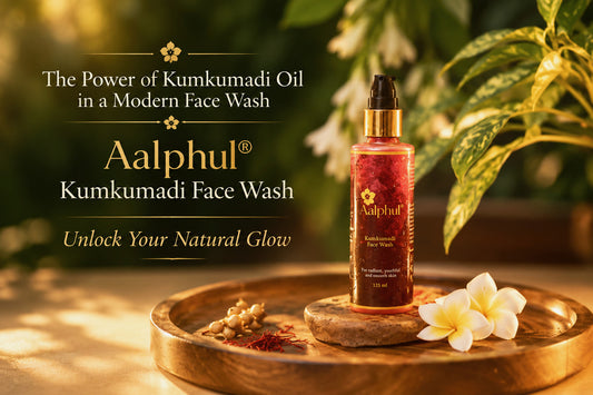 A bottle of Aalphul Kumkumadi Face Wash stands on a wooden tray with a flower and spices, set against a warm, sunlit background with green leaves and white flowers. Text on the left reads 'The Power of Kumkumadi Oil in a Modern Face Wash' and 'Aalphul Kumkumadi Face Wash'.