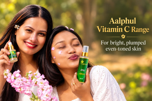 Two women outdoors holding green Aalphul Vitamin C Range skincare bottles, with pink flowers in the foreground and promotional text on the right.